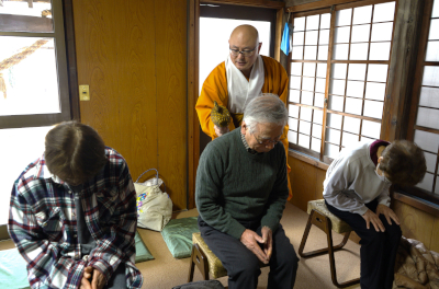 ５円玉で作られた小づちで参拝者の肩に触れ、開運を祈る谷山住職（１０日、延岡市古城町）