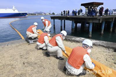 流出油防除訓練で協力してオイルフェンスを延ばす職員ら